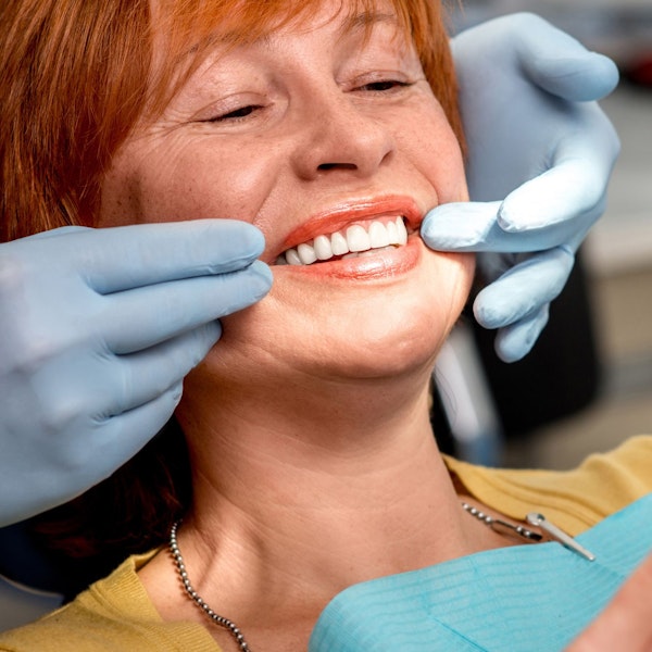 Smiling woman looking at face after full mouth reconstruction