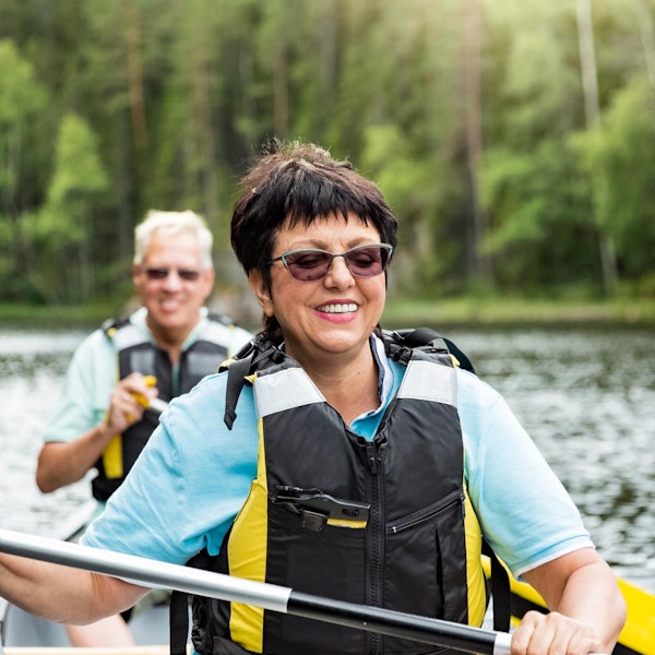Mature woman kayaking and smiling with man in kayak