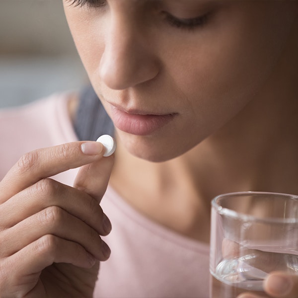 Woman lifting pill to mouth